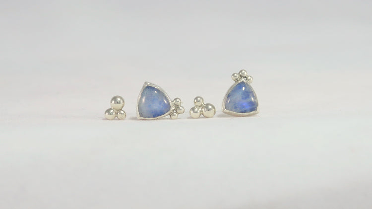 2 pairs of stud earrings. One pair is 3 silver bubbles decreasing in size shaped like a pyramid. The other pair is trillion rainbow moonstones with three bubbles on one of the points.
