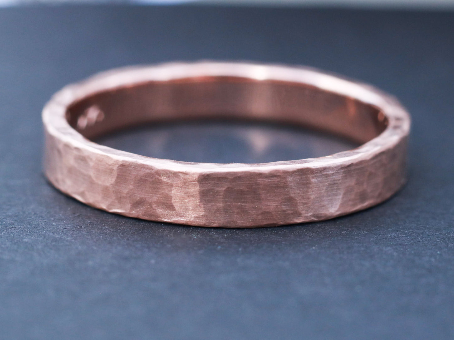 Solid 14k gold ring band measuring 4mm wide, textured with a hammer and finished with a matte surface.