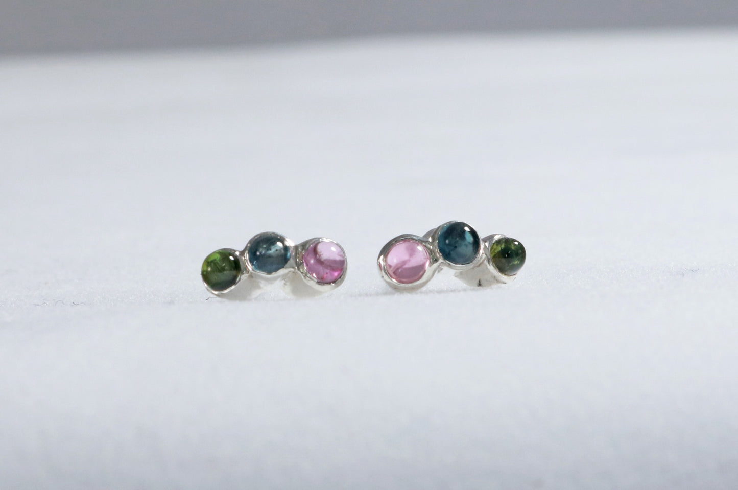 Stud earrings, 3 round natural gemstones set in sterling silver bezels on a curve.