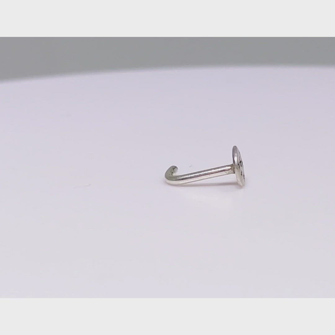 A video of a 5mm, flat, solid sterling silver disc nose stud with black hand carved stars.