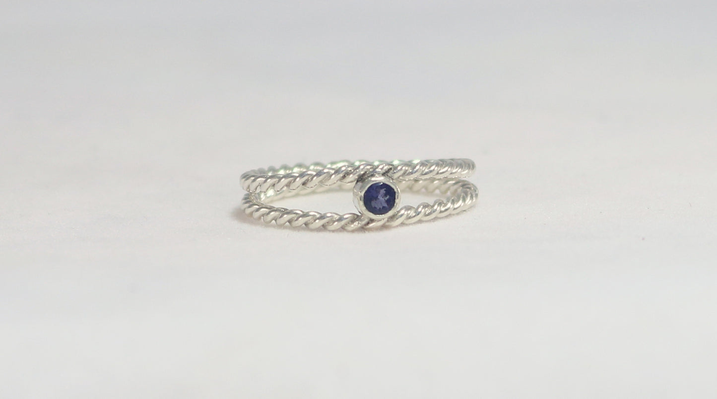 Round natural gemstone set in a sterling silver bezel between two twisted silver ring bands.