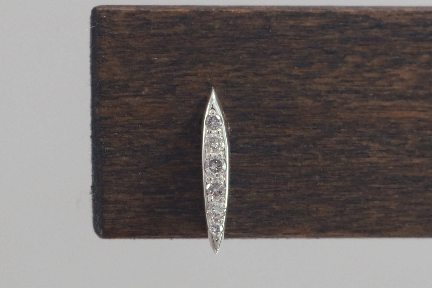 Studs made from solid sterling silver, shaped like a pointed ellipse, bead set with 6 diamonds descending in size.