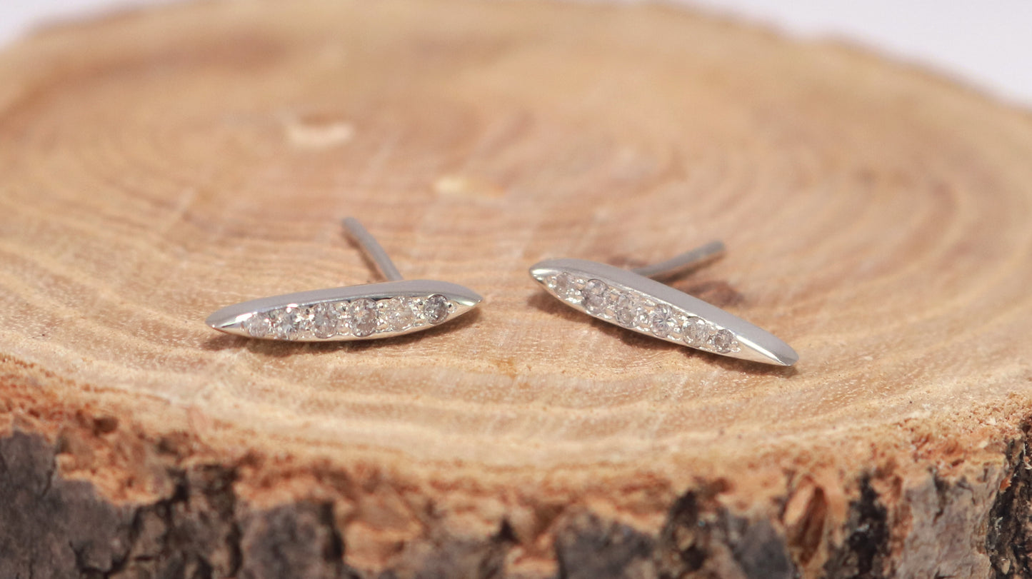 Studs made from solid sterling silver, shaped like a pointed ellipse, bead set with 6 diamonds descending in size.
