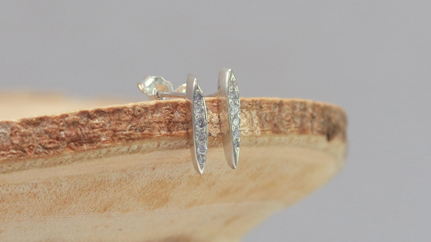 Studs made from solid sterling silver, shaped like a pointed ellipse, bead set with 6 diamonds descending in size.