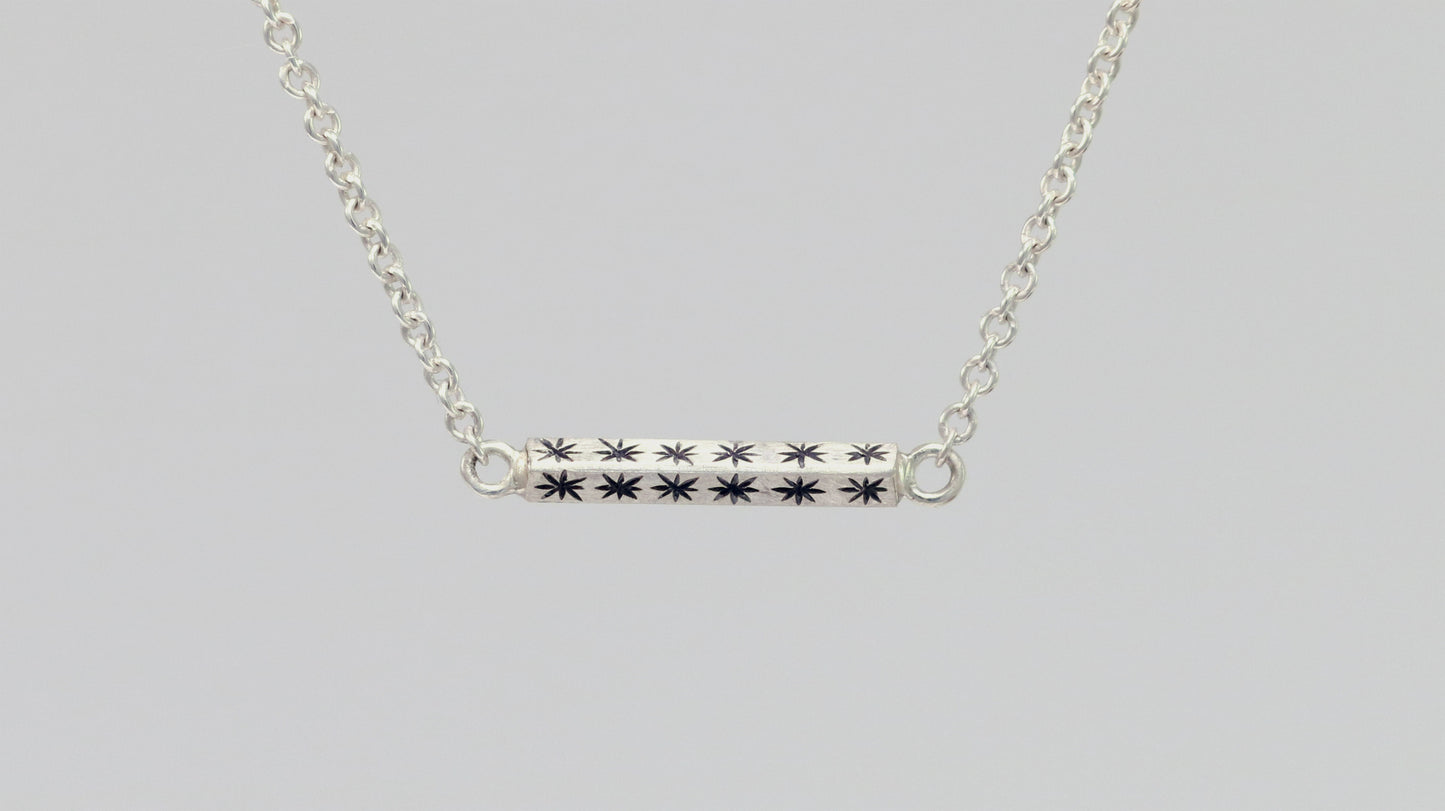 Sterling silver bar necklace with hand cut black stars on every side on a sterling silver chain.