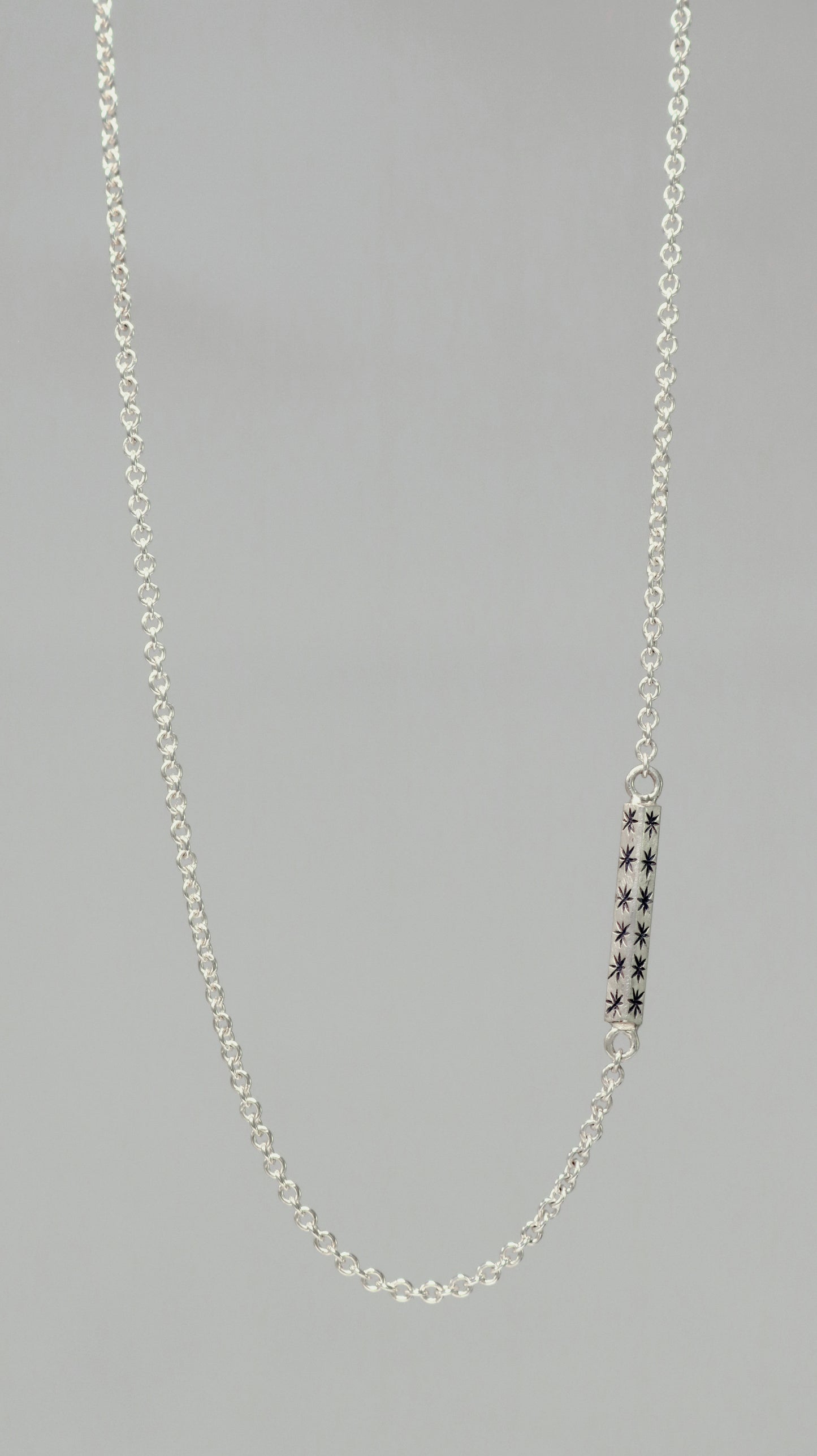 Sterling silver bar necklace with hand cut black stars on every side on a sterling silver chain.