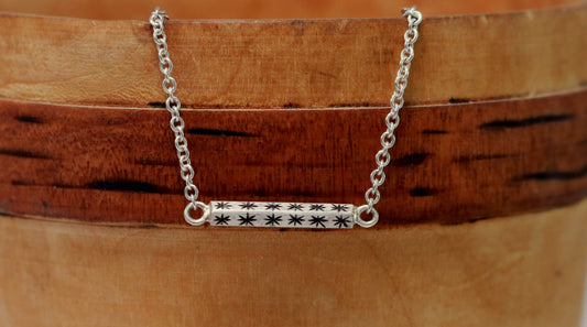 Sterling silver bar necklace with hand cut black stars on every side on a sterling silver chain.