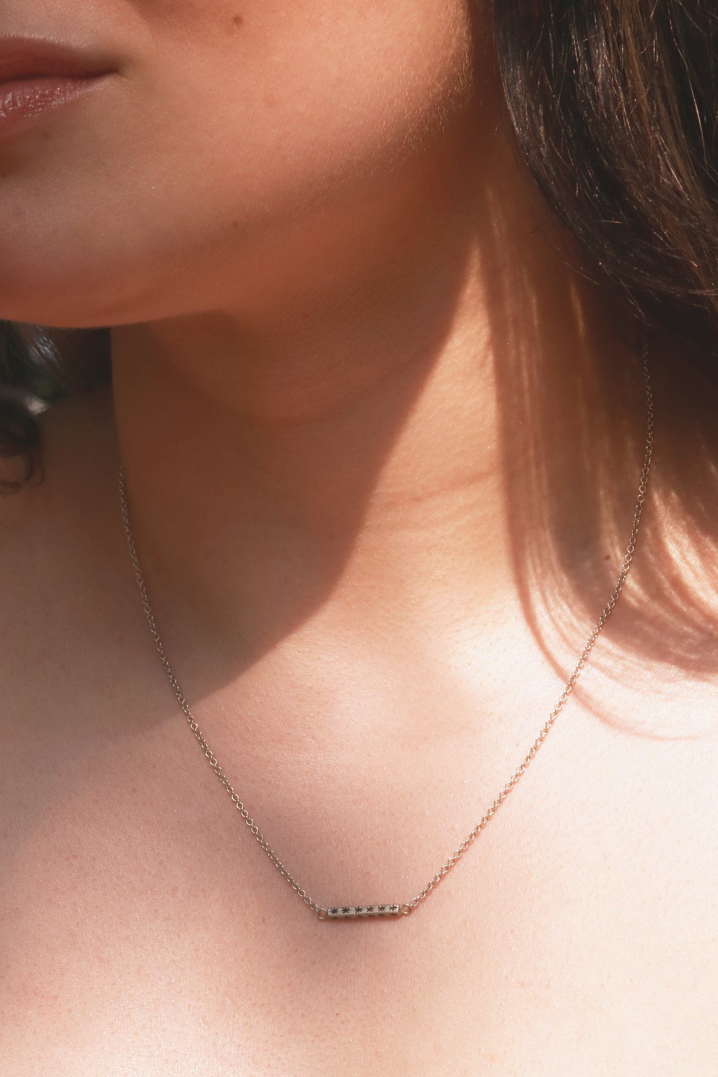 Sterling silver bar necklace with hand cut black stars on every side on a sterling silver chain.
