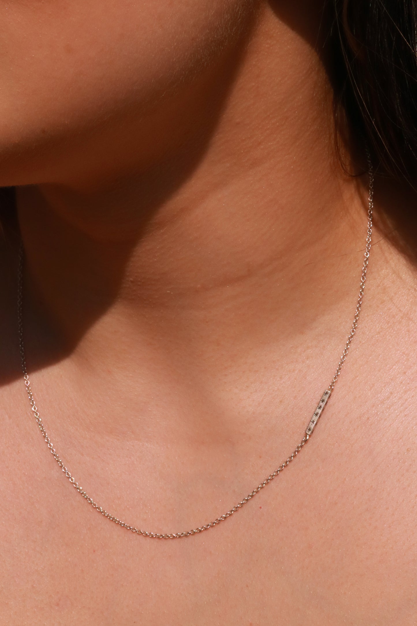 Sterling silver bar necklace with hand cut black stars on every side on a sterling silver chain.