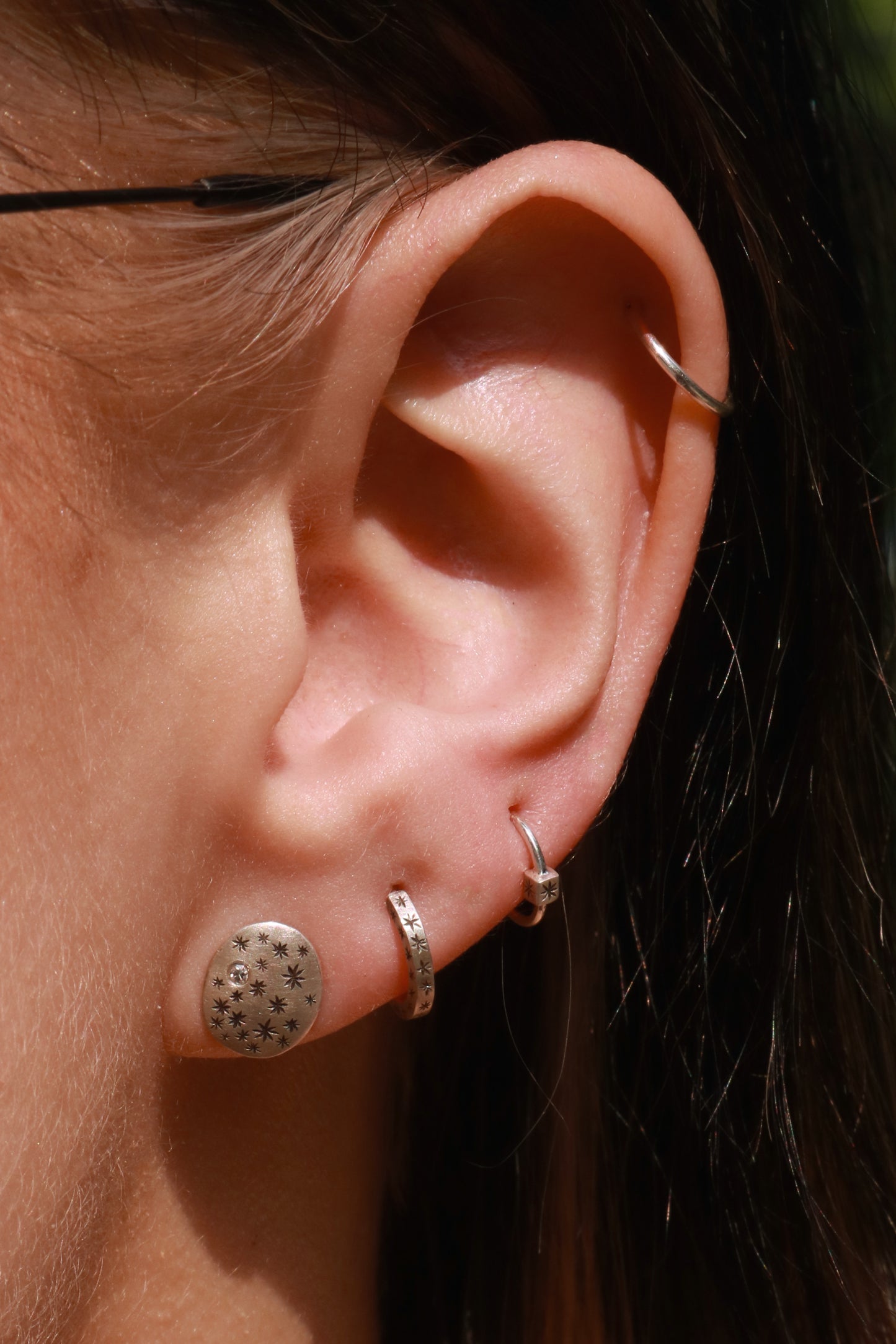 A pair of domed oval sterling silver studs covered in hand carved, black stars and one white diamond..