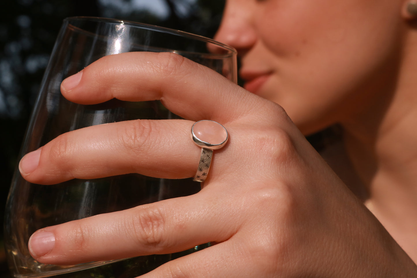 Oval natural gemstone set in sterling silver bezel on a wide sterling silver ring band with checker board of hand cut black stars on either side.
