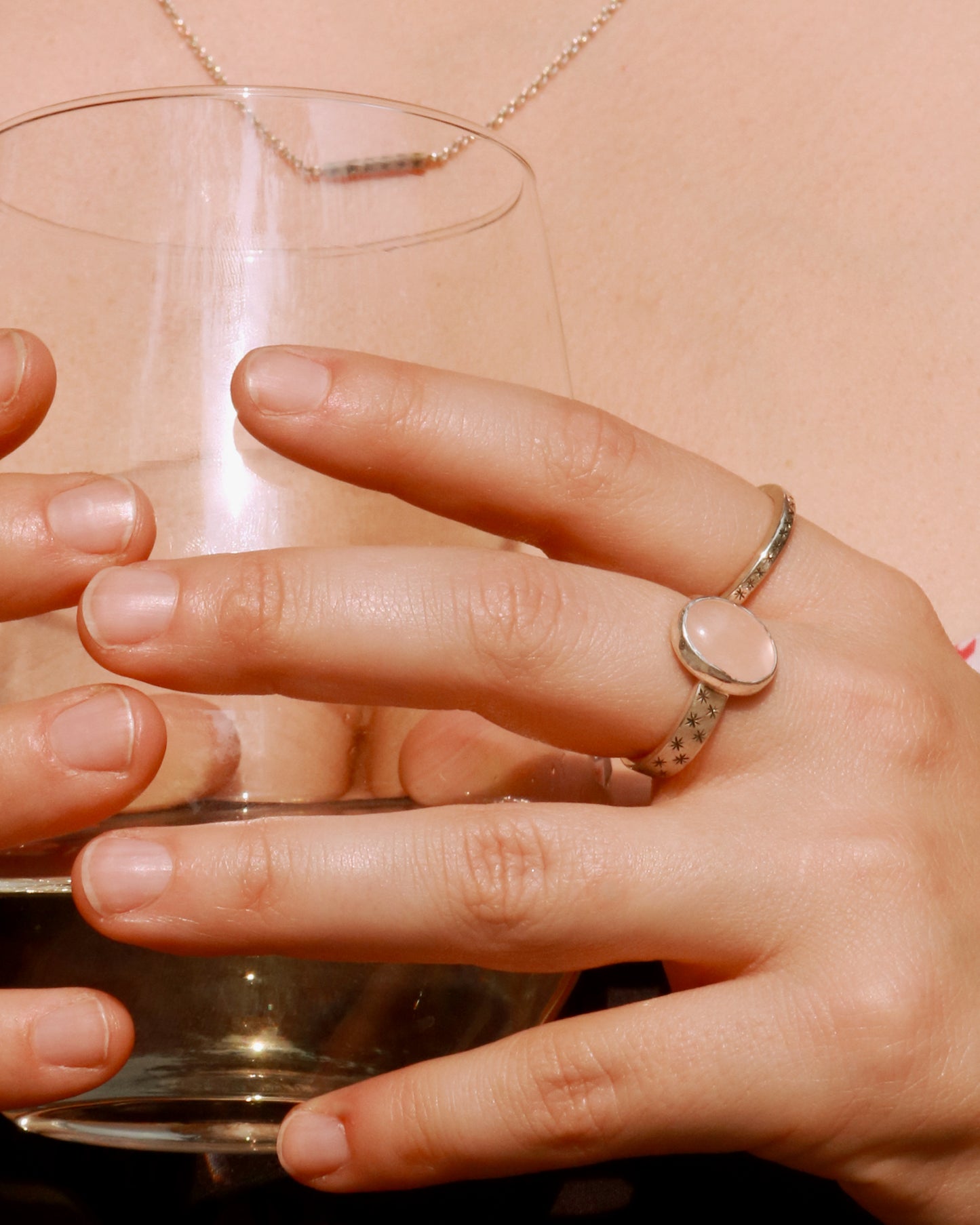 Oval natural gemstone set in sterling silver bezel on a wide sterling silver ring band with checker board of hand cut black stars on either side.