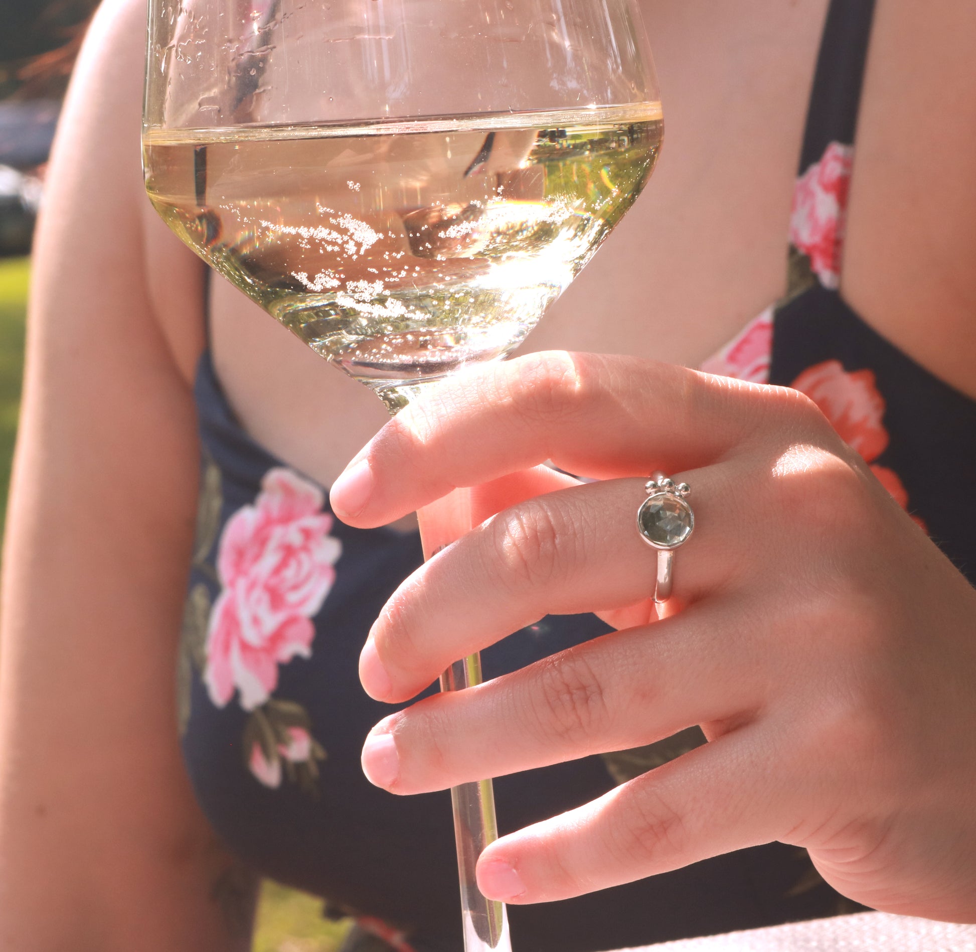A model wearing a silver ring with an 8mm round rose cut green amethyst gemstone set in sterling silver. 3 Silver bubble accents aligned along the side.