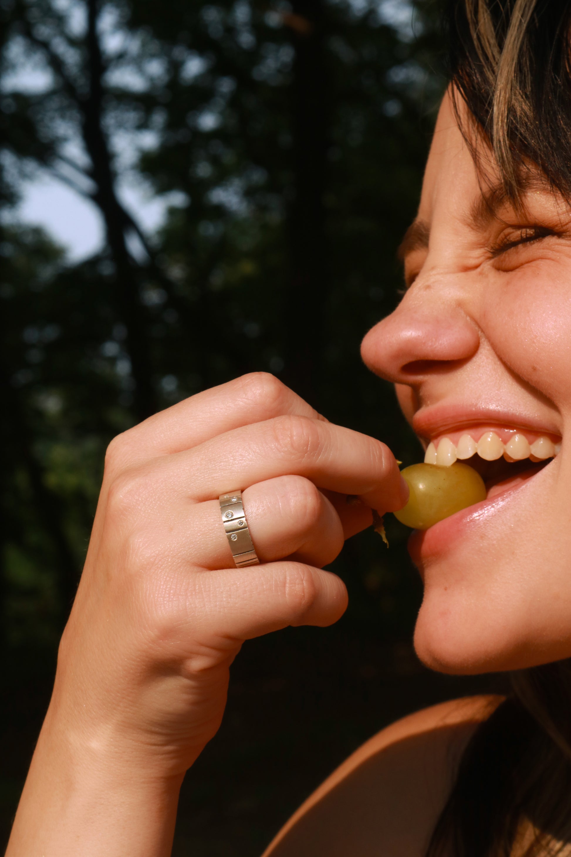 A model wearing a thick silver ring band with randomly spaced black line details is flush set with 5 various sized diamonds.