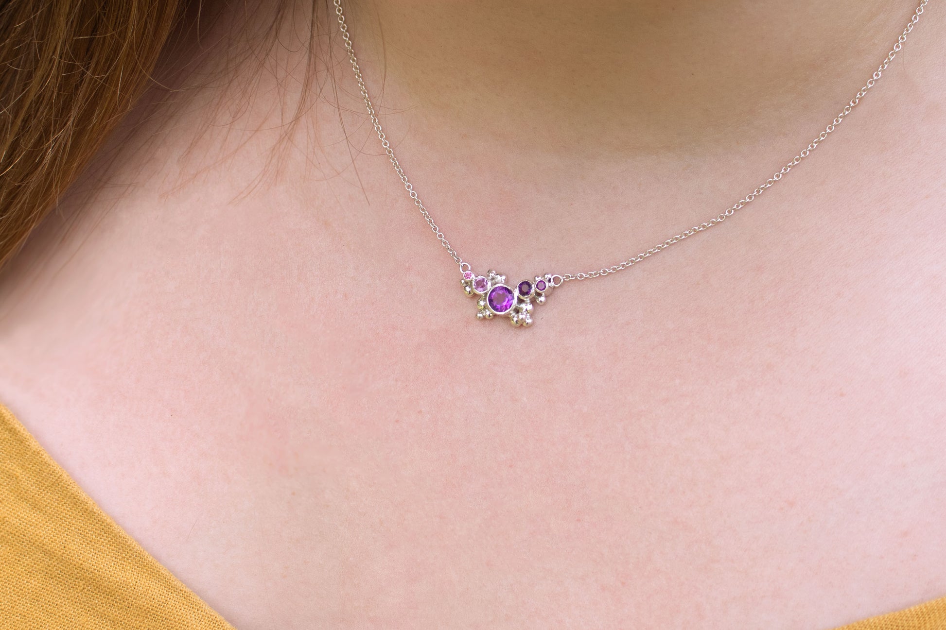 Different shades of round amethyst stones, surrounded by silver bubbles on a silver chain.