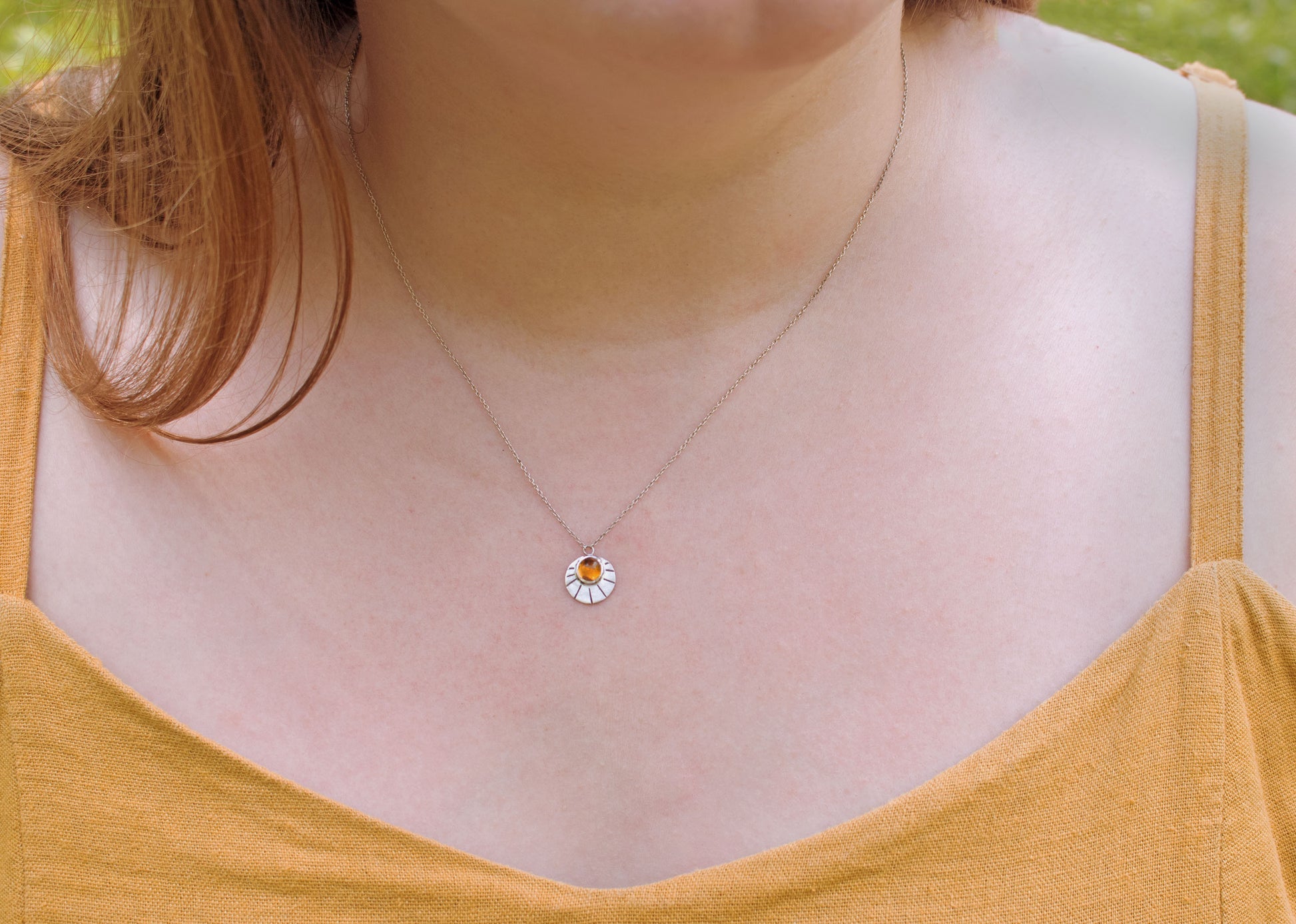 Sterling silver disc with natural gemstone set in bezel at the top with black lines bursting from it on a sterling silver chain.