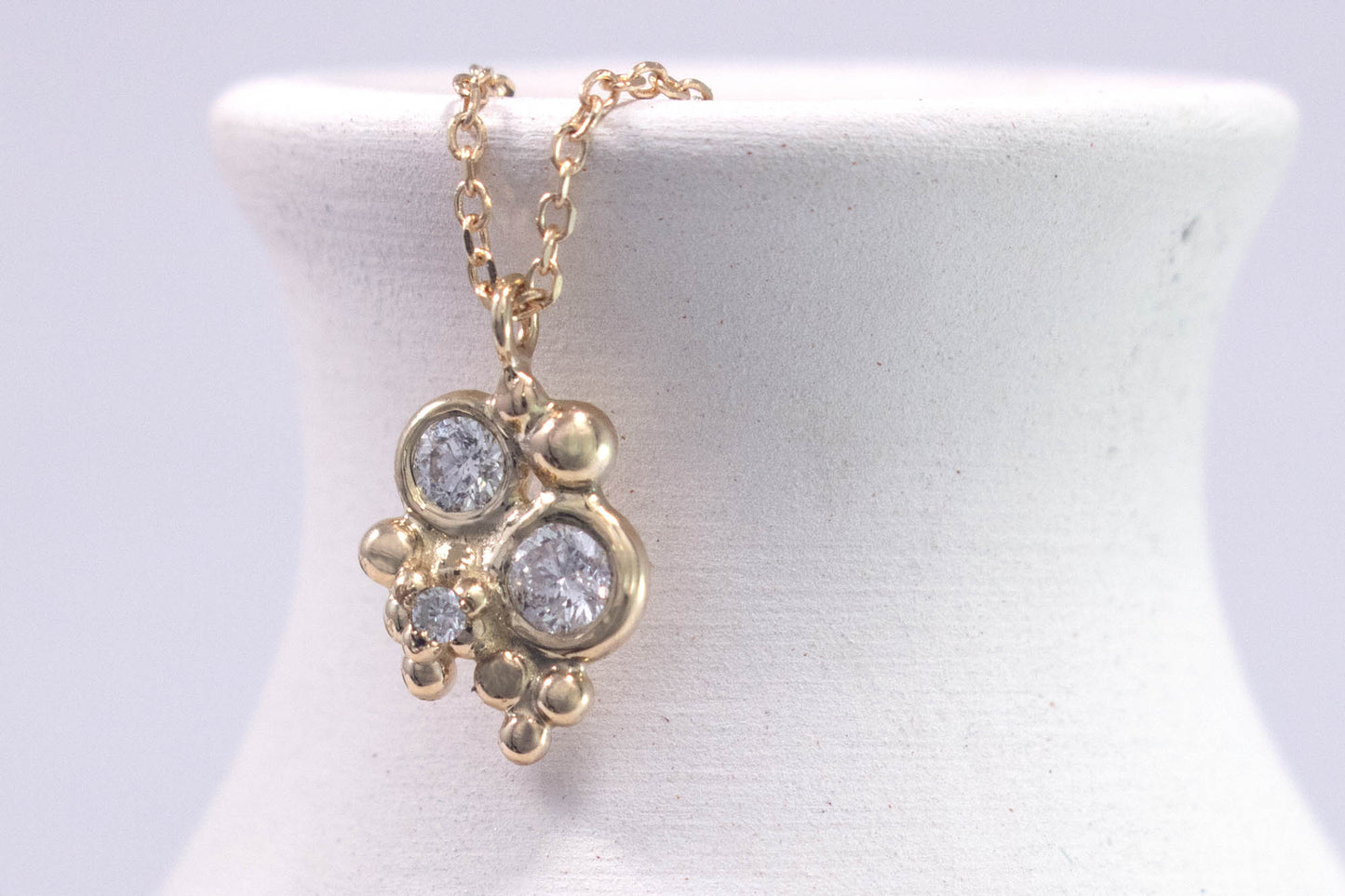 Three diamonds, decreasing in size, set in 14k yellow gold bezels, surrounded by randomly placed gold bubbles. on a 14k yellow gold chain.