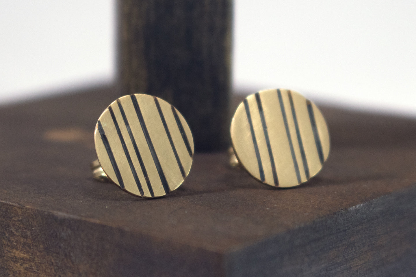 Round 14k gold disc studs with black lines randomly spaced.