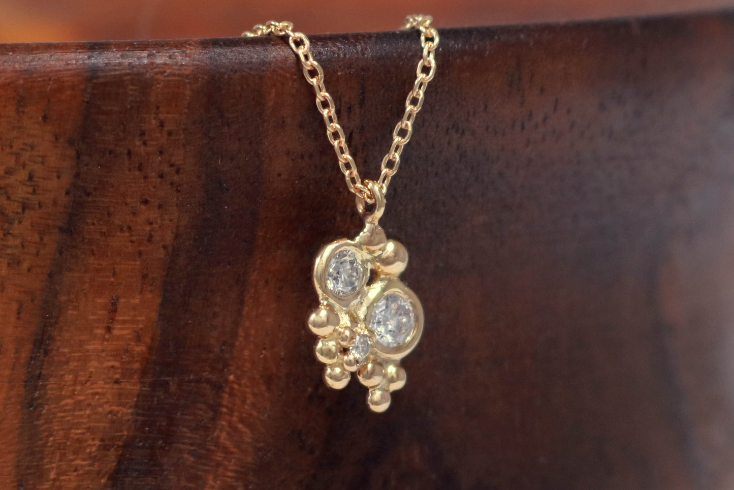 Three diamonds, decreasing in size, set in 14k yellow gold bezels, surrounded by randomly placed gold bubbles. on a 14k yellow gold chain.