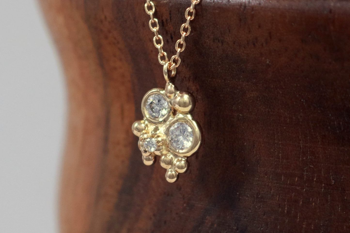 Three diamonds, decreasing in size, set in 14k yellow gold bezels, surrounded by randomly placed gold bubbles. on a 14k yellow gold chain.