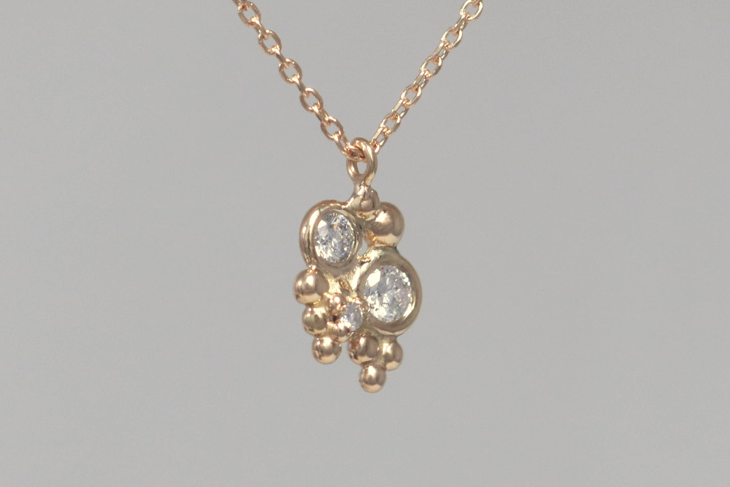 Three diamonds, decreasing in size, set in 14k yellow gold bezels, surrounded by randomly placed gold bubbles. on a 14k yellow gold chain.