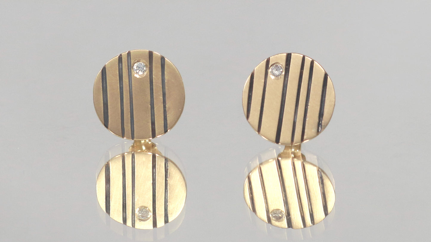 Round 14k gold disc studs with black lines randomly spaced.