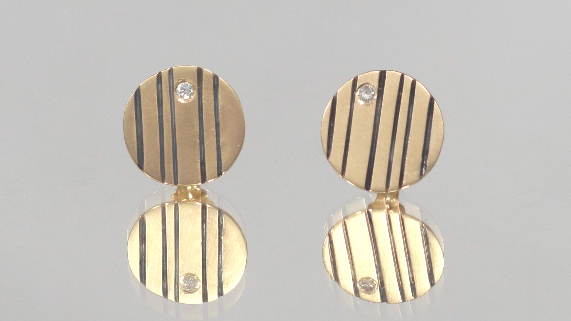 Round 14k gold disc studs with black lines randomly spaced.