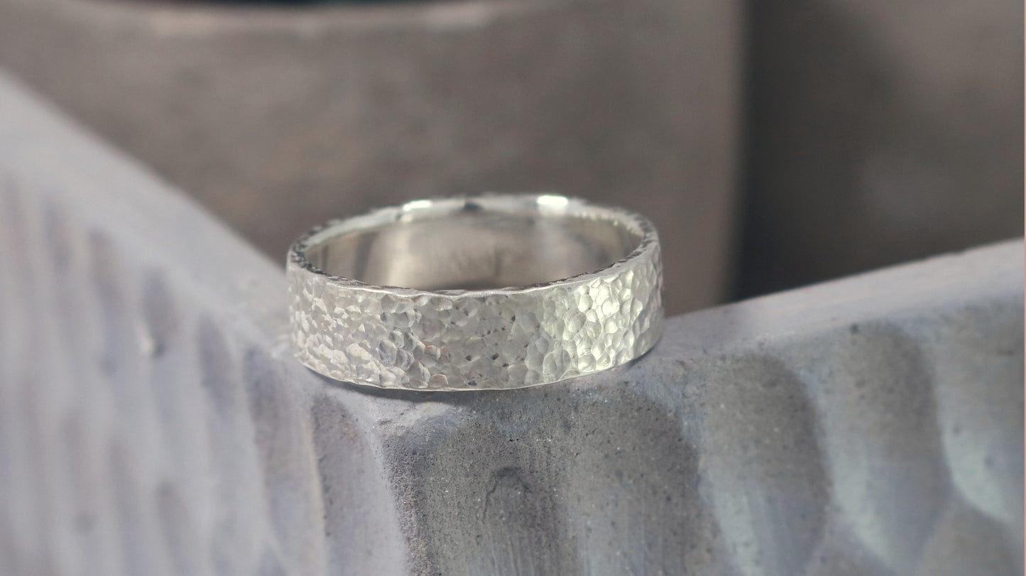 A polished solid sterling silver ring band, 6mm wide, with small dimpled hammer texture.