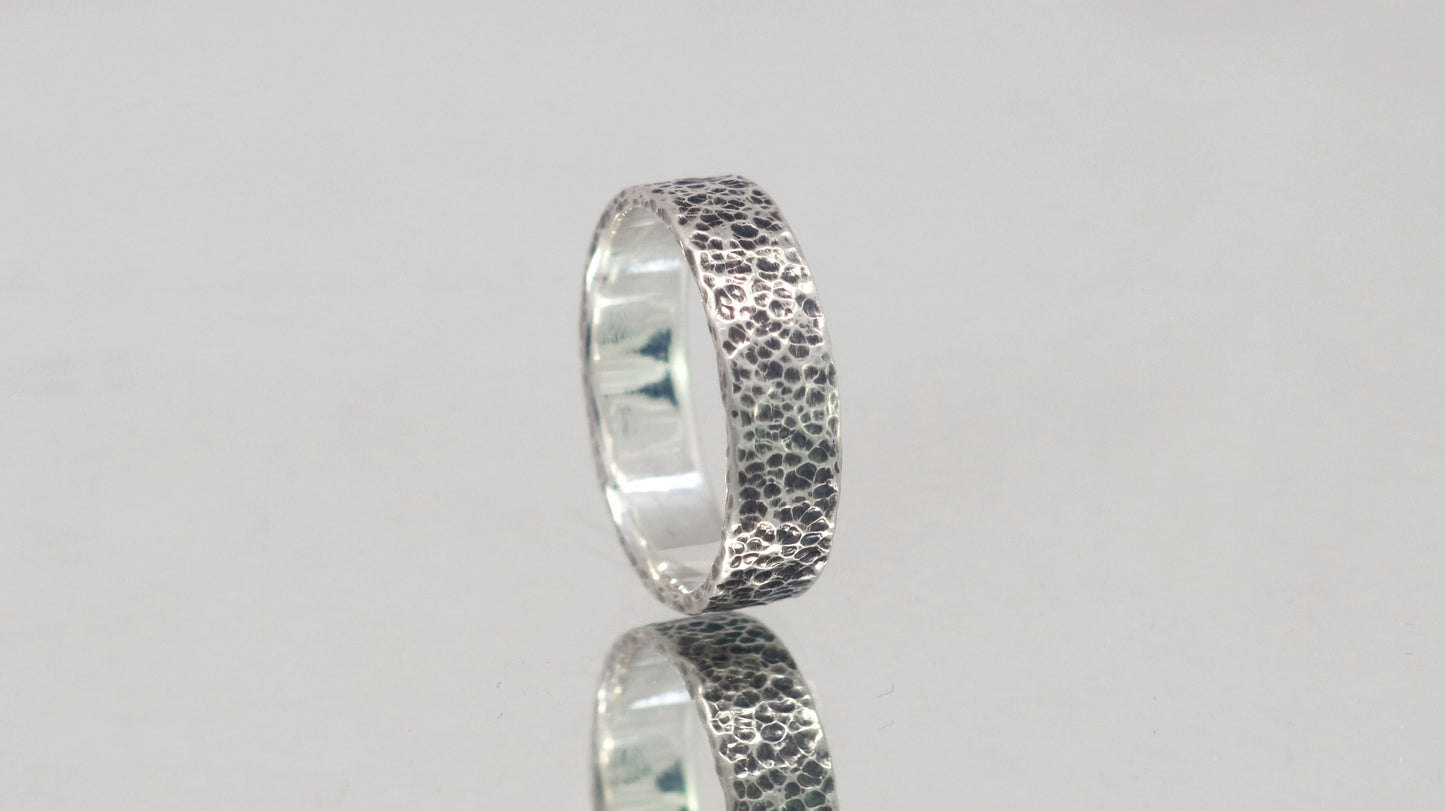 A darkened solid sterling silver ring band, 6mm wide, with small dimpled hammer texture.
