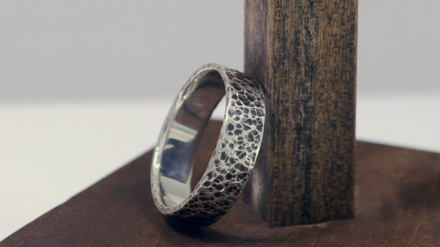 A darkened solid sterling silver ring band, 6mm wide, with small dimpled hammer texture.