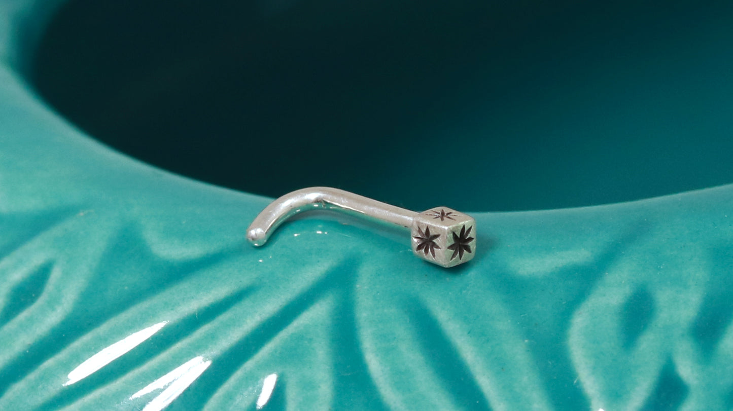 A solid sterling silver cube on a 18g L post nose ring with a hand carved black star on each side.