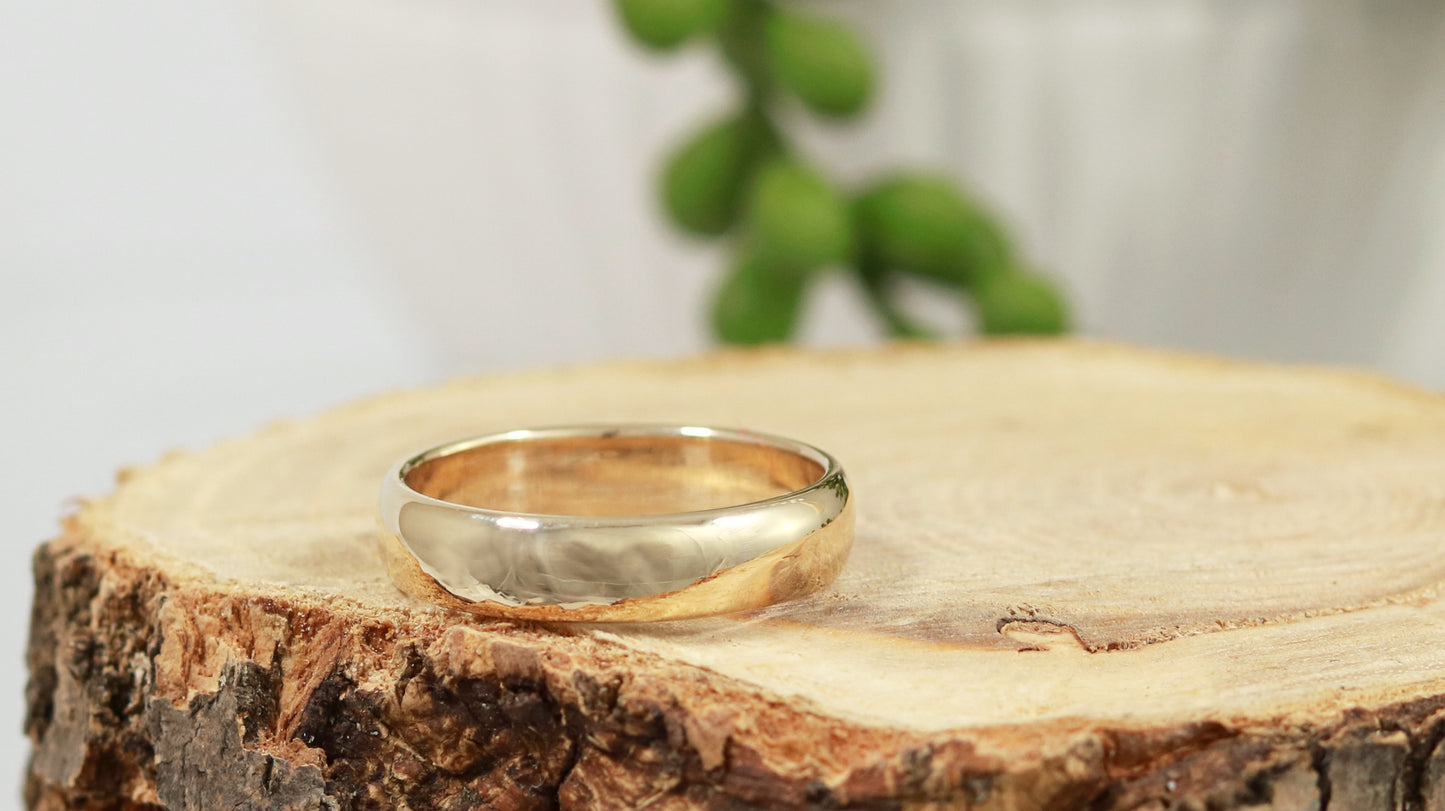 A slightly domed, polished, solid 14k yellow gold ring band, 5mm thick.