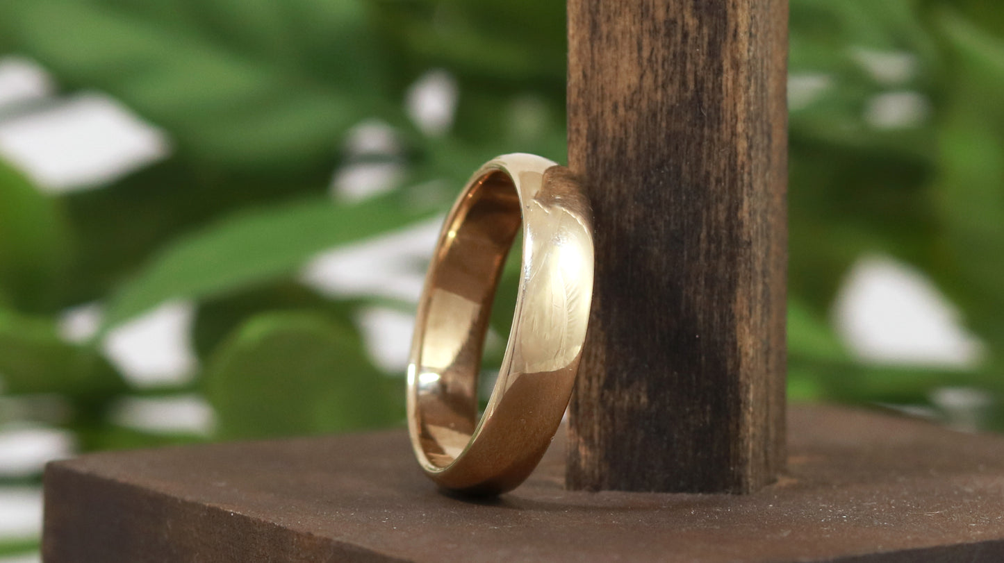 A slightly domed, polished, solid 14k yellow gold ring band, 5mm thick.