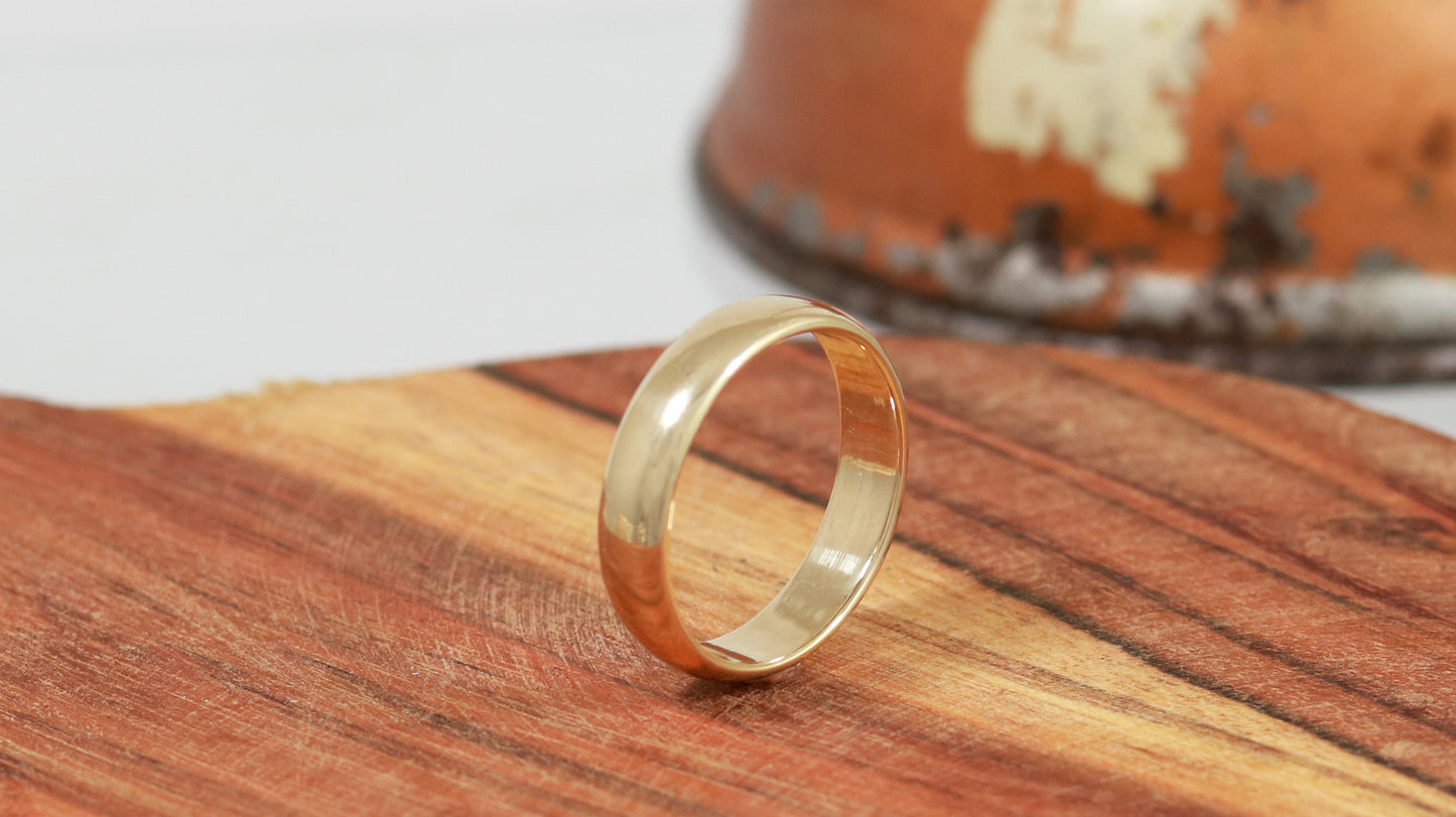A slightly domed, polished, solid 14k yellow gold ring band, 5mm thick.