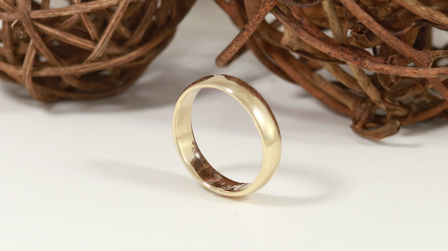 A slightly domed, polished, solid 14k yellow gold ring band, 5mm thick.