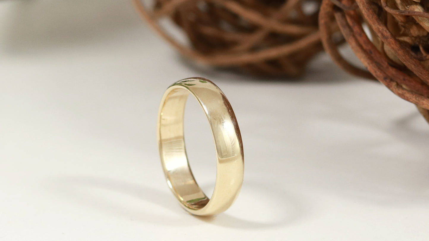 A slightly domed, polished, solid 14k yellow gold ring band, 5mm thick.