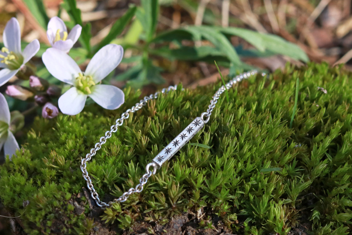 Sterling silver bar necklace with hand cut black stars on every side on a sterling silver chain.