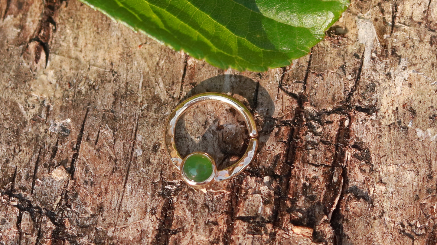 A 14k yellow gold hoop, flattened and textured at the bottom, with a round jade set in a bezel on top of the textured flat section.
