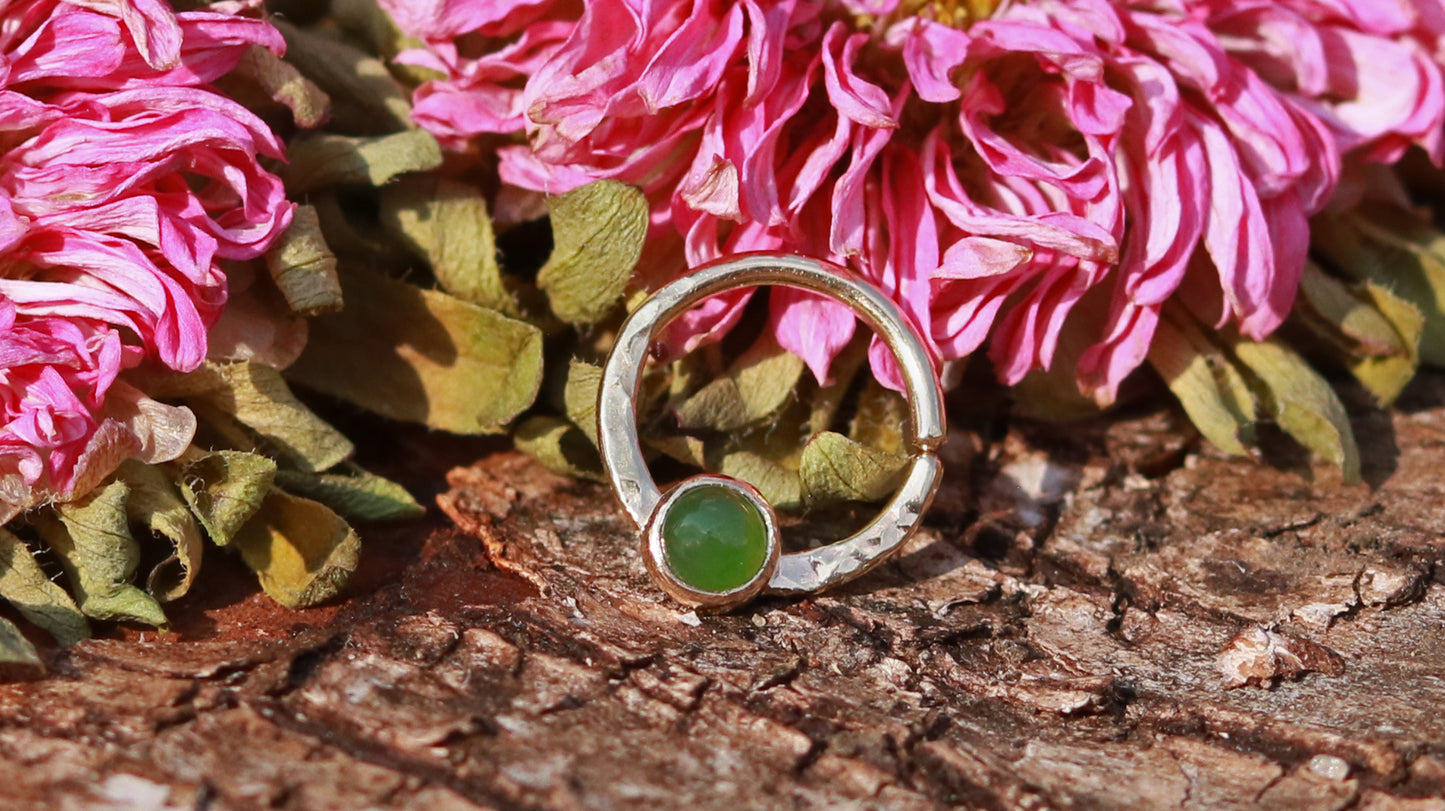 A 14k yellow gold hoop, flattened and textured at the bottom, with a round jade set in a bezel on top of the textured flat section.