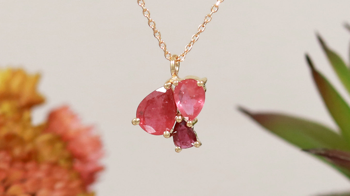 3 natural pear rubies in different shades of red set in solid 14k yellow gold on a gold chain.