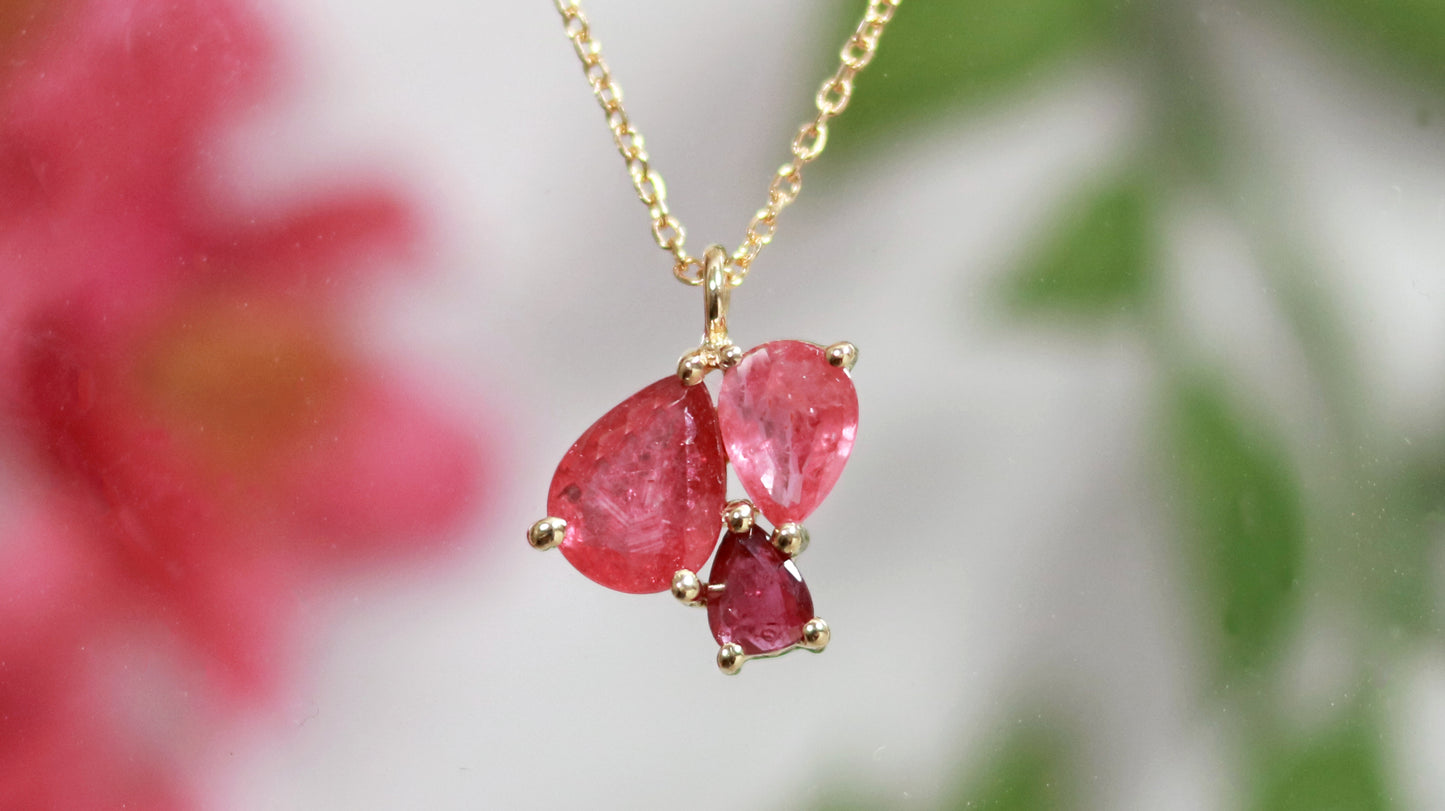 3 natural pear rubies in different shades of red set in solid 14k yellow gold on a gold chain.