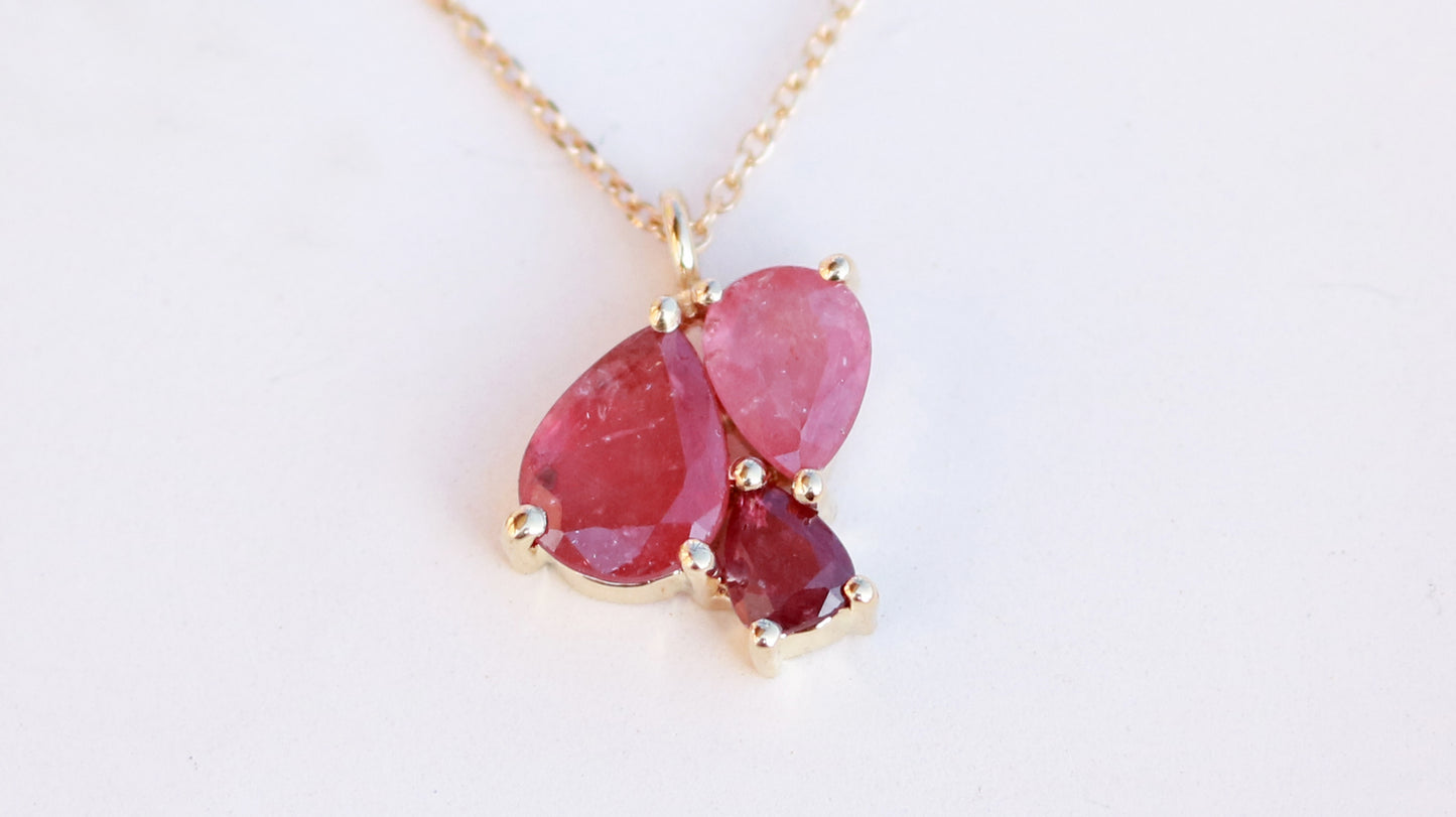 3 natural pear rubies in different shades of red set in solid 14k yellow gold on a gold chain.