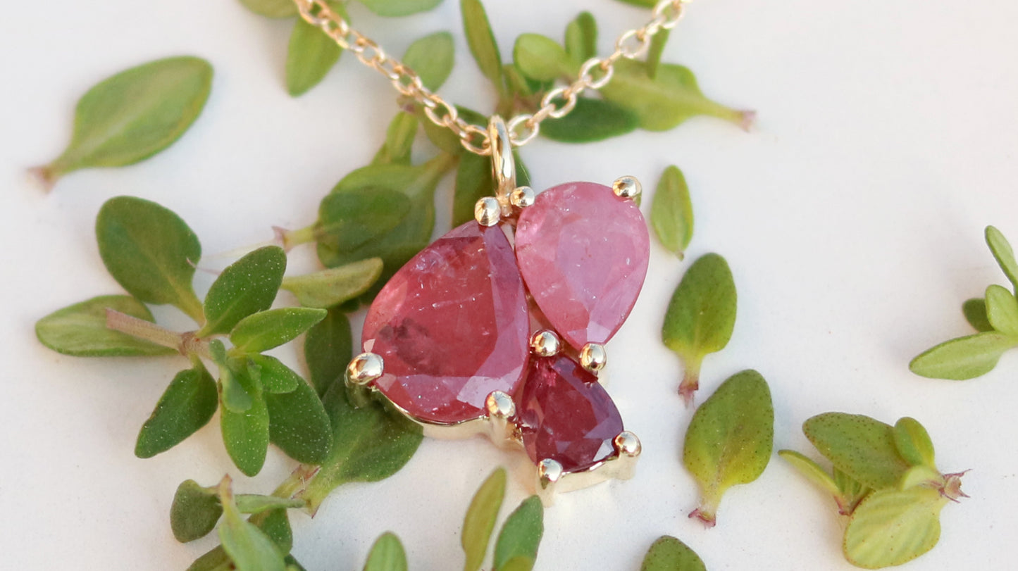 3 natural pear rubies in different shades of red set in solid 14k yellow gold on a gold chain.