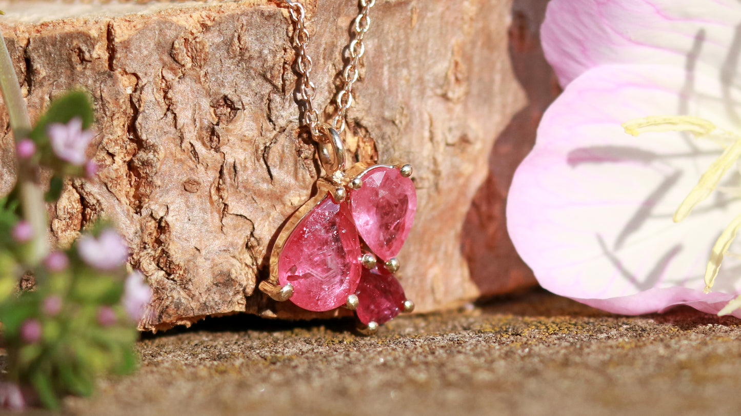 3 natural pear rubies in different shades of red set in solid 14k yellow gold on a gold chain.