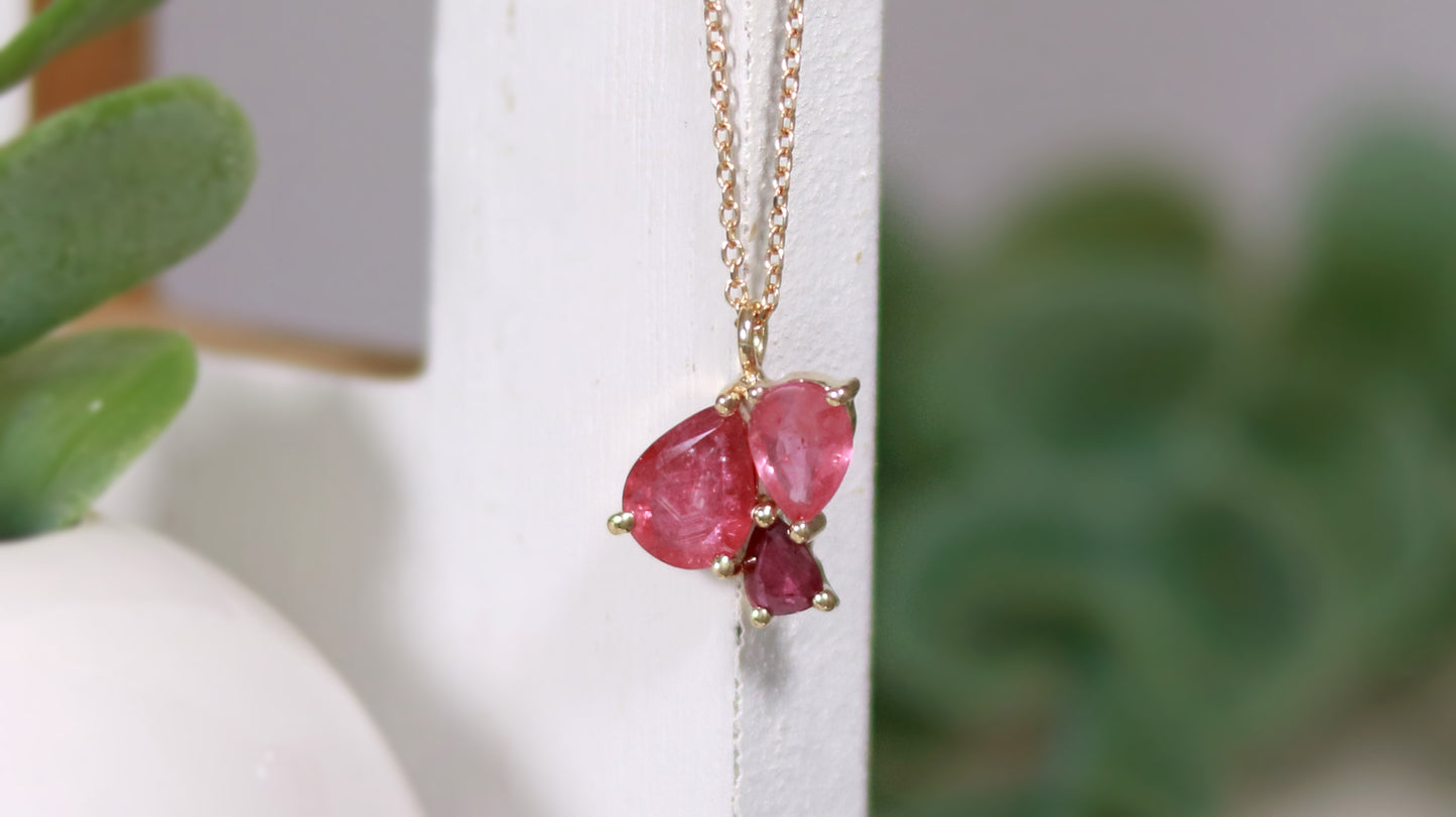 3 natural pear rubies in different shades of red set in solid 14k yellow gold on a gold chain.