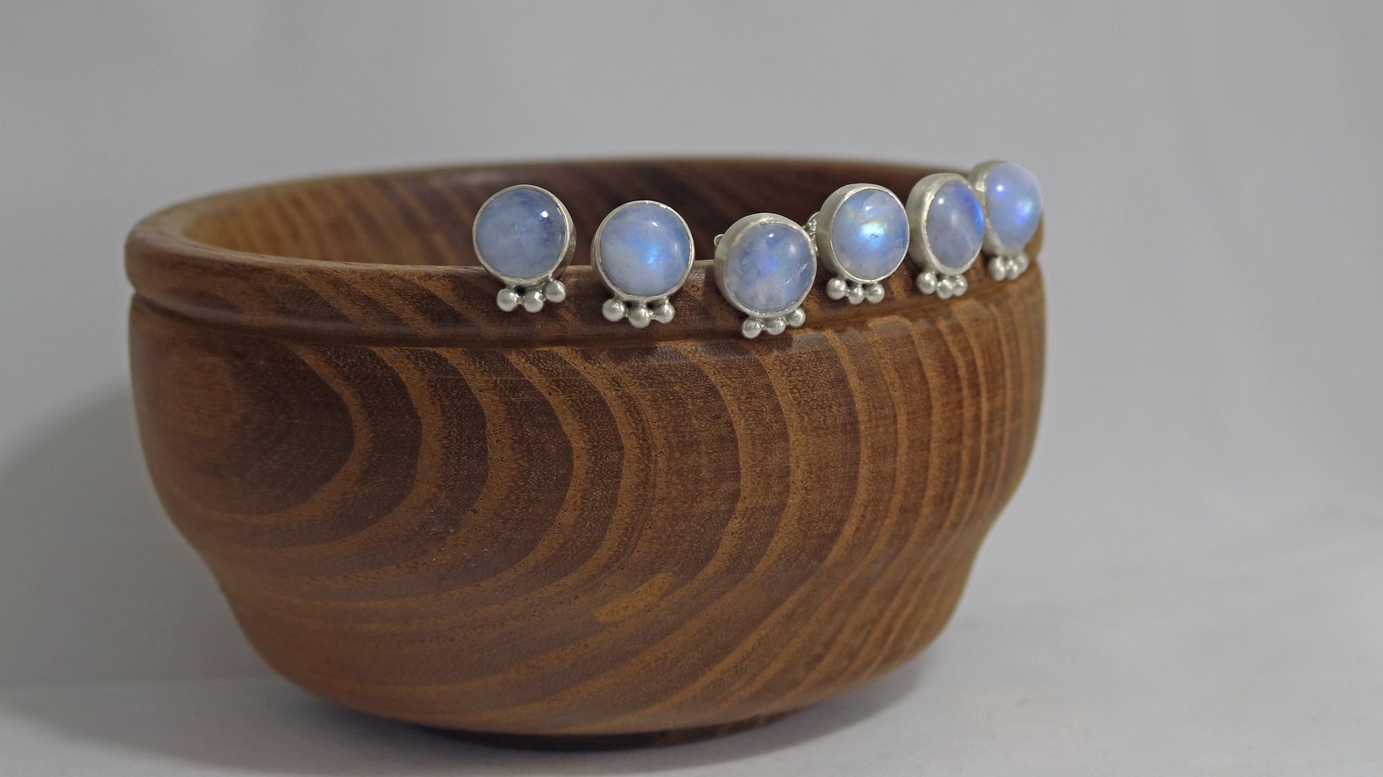 Three pairs of round rainbow moonstone stud earrings with 3 silver bubbles in a row at the bottom.