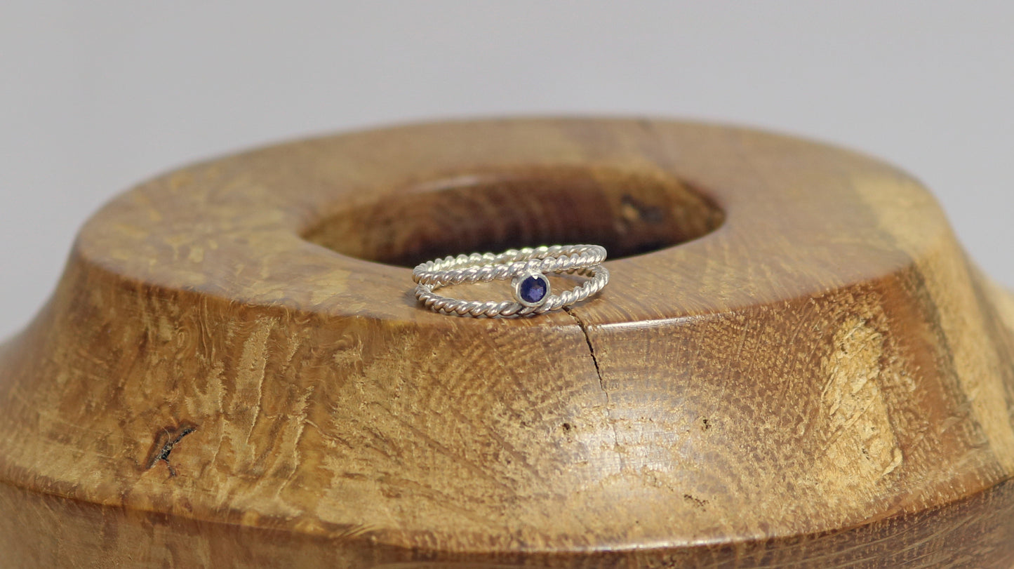 Round natural gemstone set in a sterling silver bezel between two twisted silver ring bands.