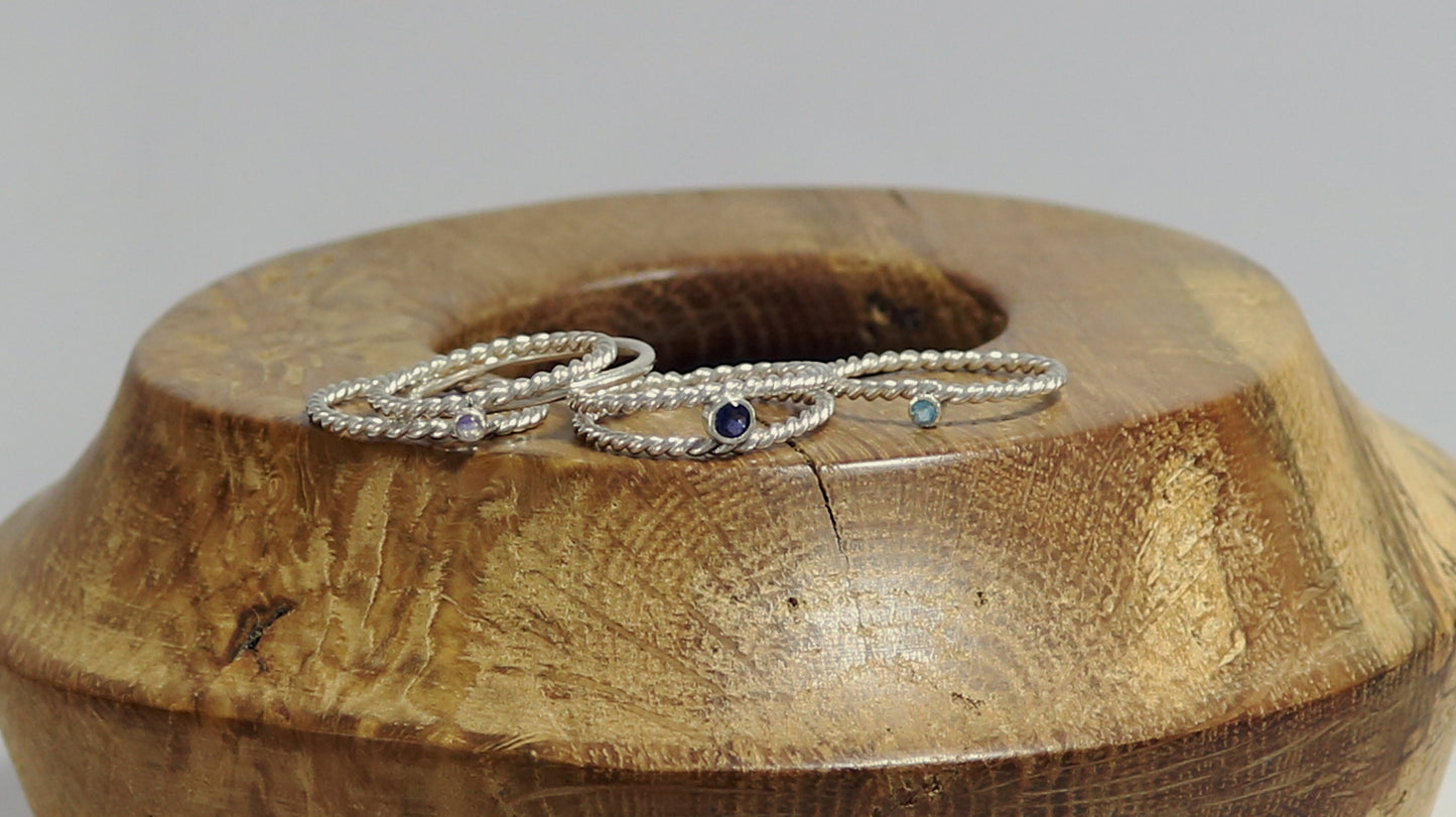 Round natural gemstone set in a sterling silver bezel between two twisted silver ring bands.