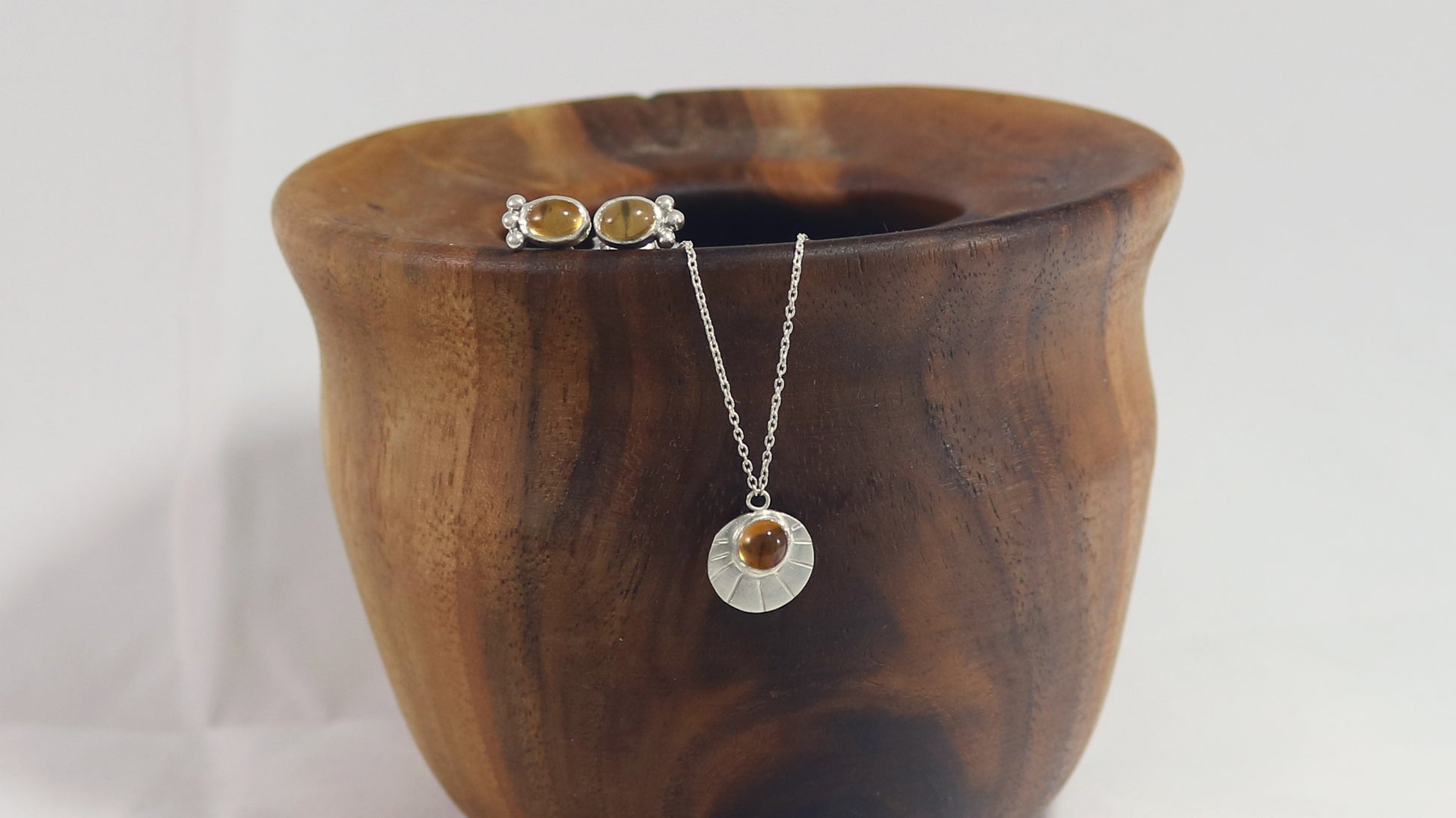 Sterling silver disc with natural gemstone set in bezel at the top with black lines bursting from it on a sterling silver chain.