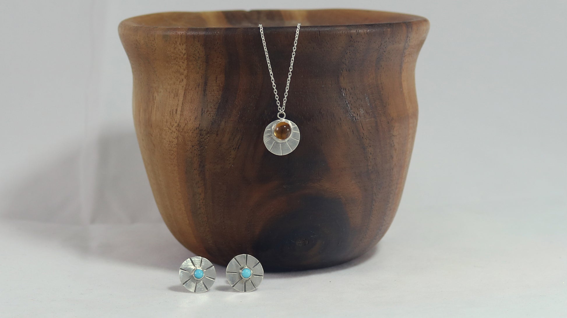 Sterling silver disc with natural gemstone set in bezel at the top with black lines bursting from it on a sterling silver chain.